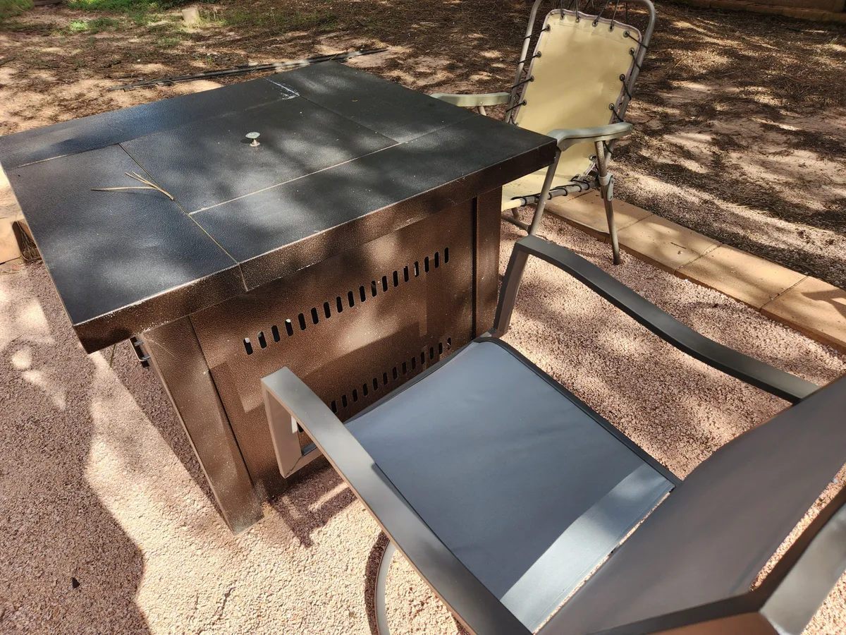 A cozy outdoor setting with a fire pit table surrounded by comfortable chairs, perfect for evening gatherings or relaxation. The arrangement invites conversation and socializing, reinforcing the idea of making memories in a shared space.