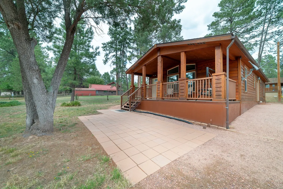 A spacious wooden porch and tiled patio overlook lush greenery, offering a peaceful transition between indoor comfort and the natural surroundings. The open setting is perfect for enjoying sunset views or stargazing at night, with plenty of room for couples to unwind and reconnect.