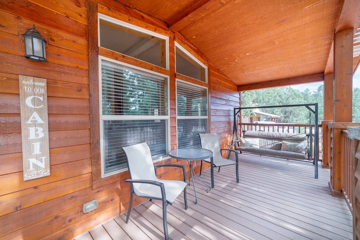 The wooden cabin exterior, complete with a hanging swing and a small table and chairs on the porch. The setup invites guests to relax and enjoy the natural surroundings, with the porch positioned as the perfect spot for morning coffee and wildlife viewing.